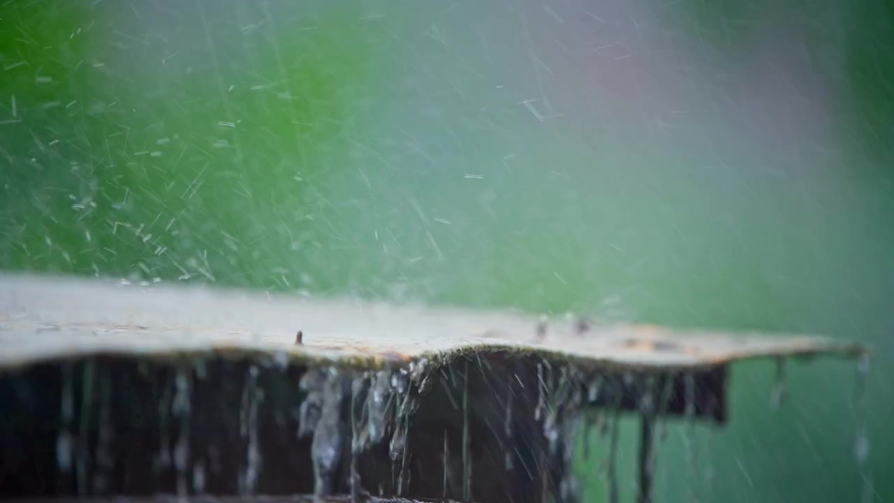Raindrops Splashing on a Roof with a Blurred Green Background