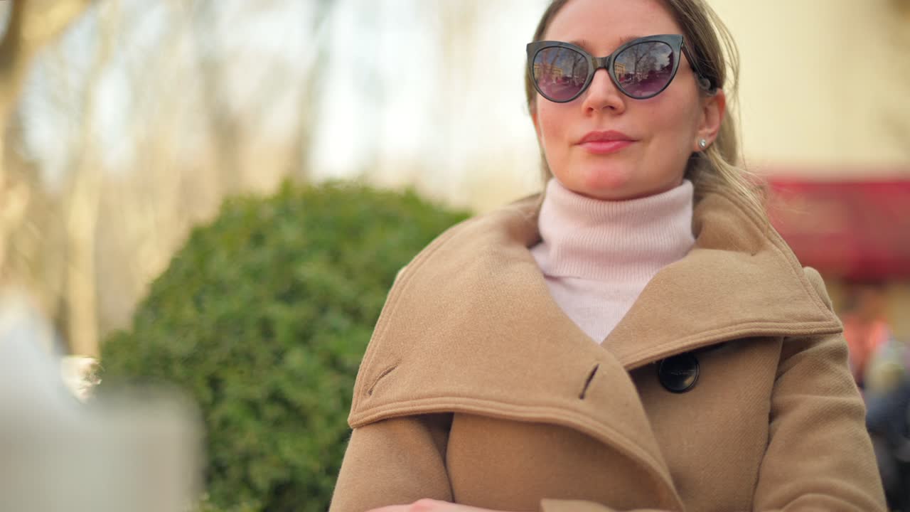 Donna mora con cappotto marrone seduta a una terrazza