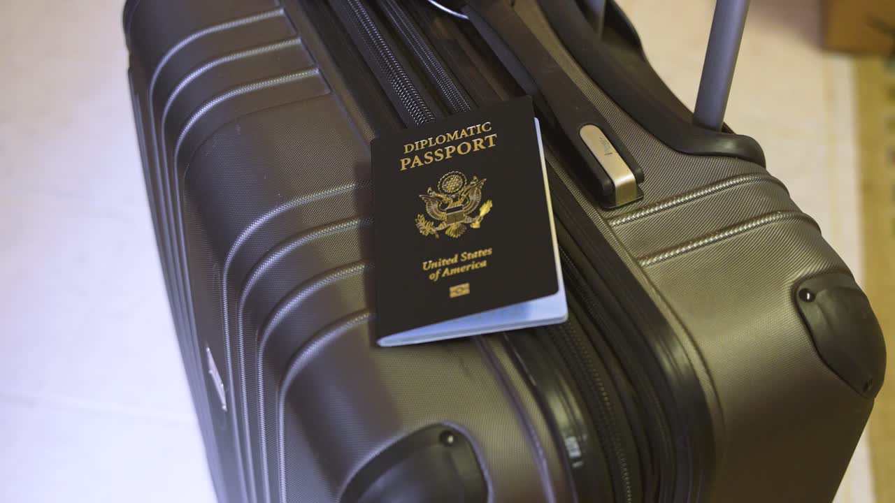 United States diplomatic passport on top of a suitcase roller luggage