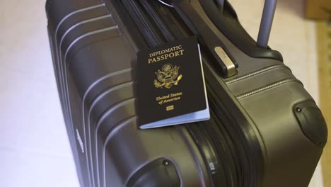 united states diplomatic passport on top of a suitcase roller luggage