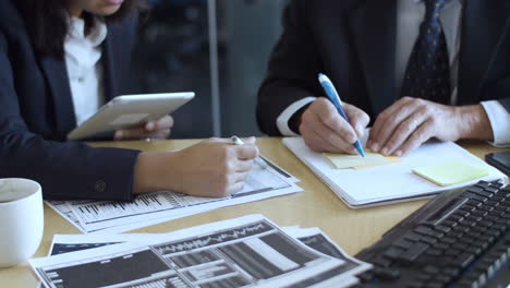 financial brokers using tablet and writing notes