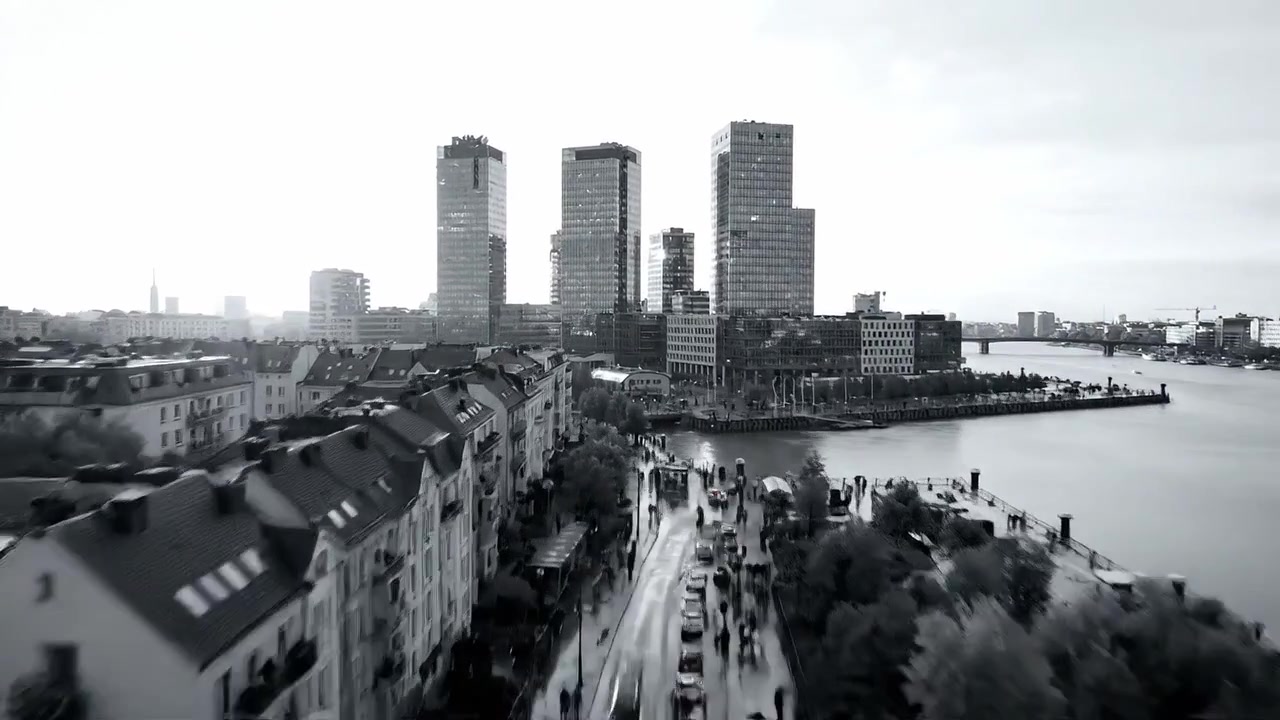 Stadsvy med modern arkitektur, livliga gator och utsikt över vattnet under en molnig himmel, som fångar storstadslivets dynamiska väsen.