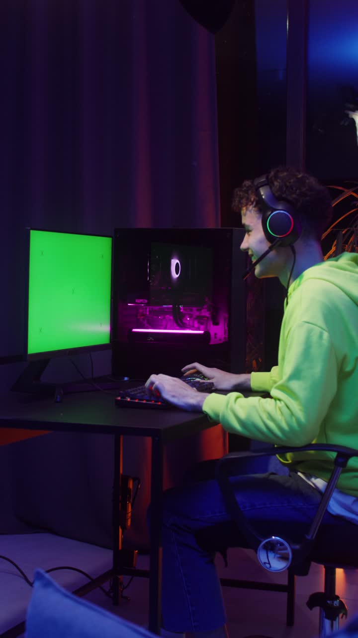 Gamer playing video game on computer with green screen monitor