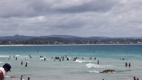 crowded beach scene with surfers and swimmers