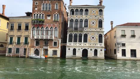 tourists on private motor boat sailing in venice, venetian houses in background
