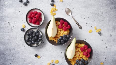 golden cornflakes with fresh fruits of raspberries  blueberries and pear in ceramic bowl