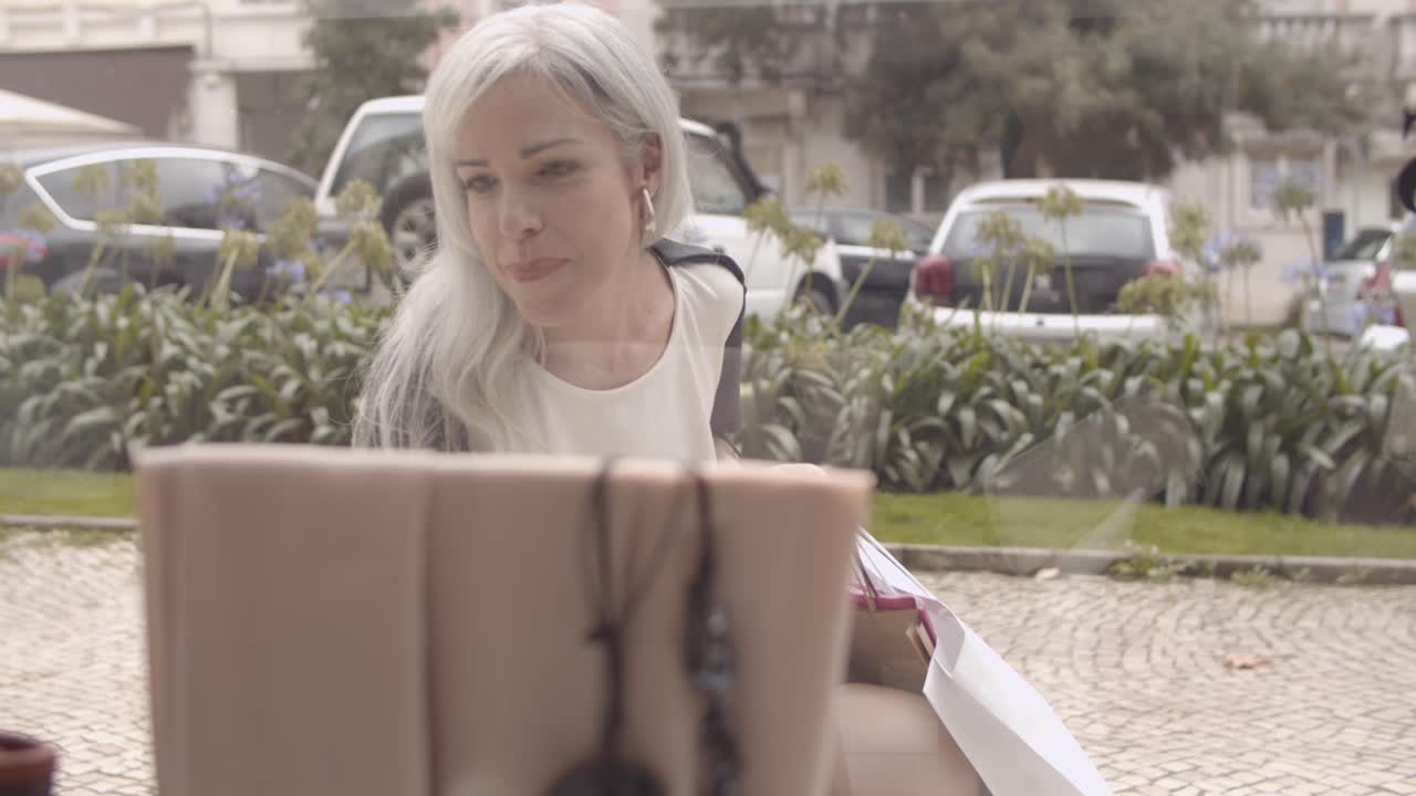 взволнованный шопоголик держит пакеты с покупками и смотрит на витрину магазина