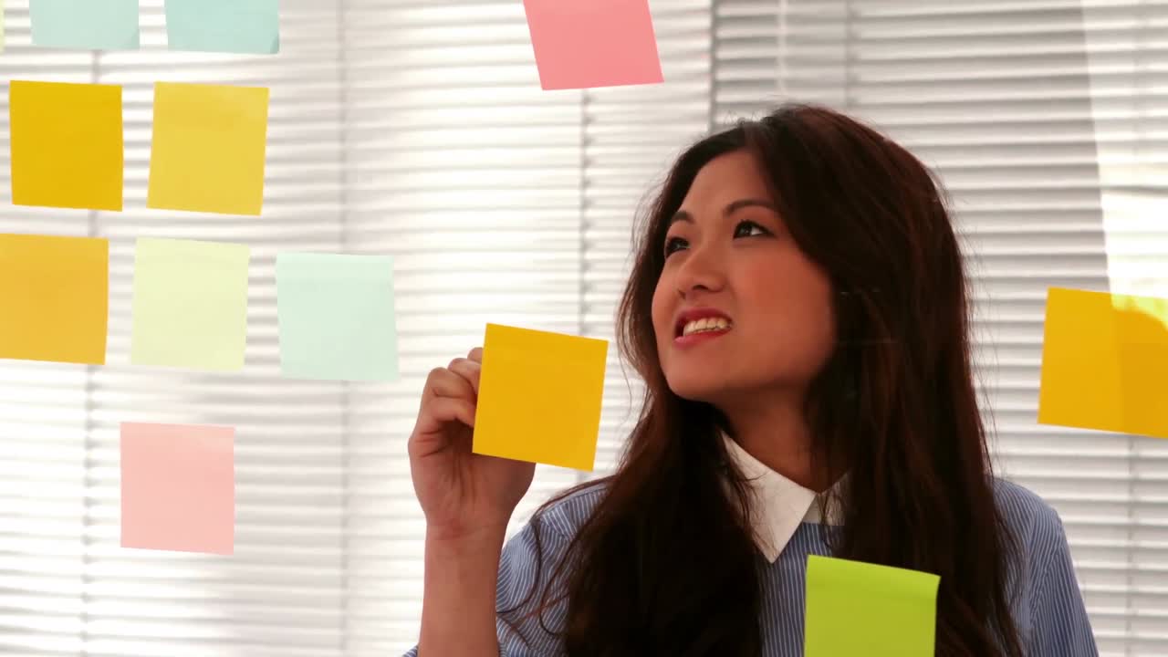 Casual businesswoman writing on post it