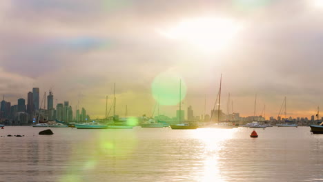 Hermoso-Destello-De-Lente-Con-Sol-Matutino-Junto-Al-Agua-Que-Se-Desplaza-Por-El-Horizonte-De-La-Ciudad