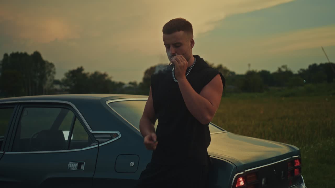 Man Smoking Cigarette by Vintage Car at Sunset