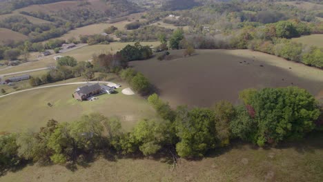 Aerial-orbit-over-southeast-USA,-Tennesee-rural-landscape-with-fields-and-farms-in-early-autumn