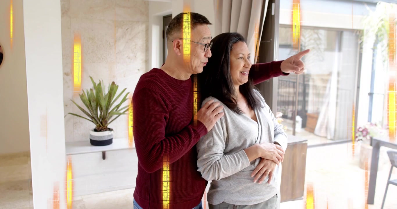 Senior man approaching partner at glass doors and hugging before pointing outside with curtains