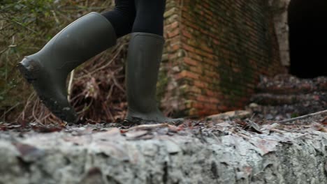 chica camina en el barro de azufre con botas verdes antes de entrar en la vieja mina, toma de cerca