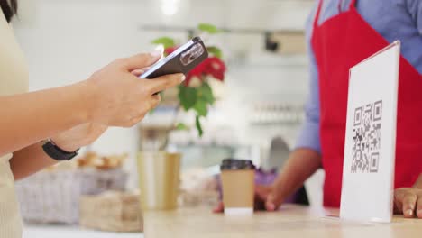 video de las manos de una mujer biracial escaneando un código qr con un teléfono inteligente