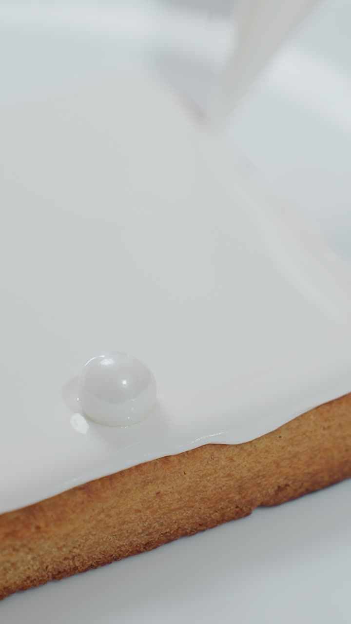 부드러운 색 glaze와 함께 베이커 아이싱 쿠키의 클로즈업, 색 부서질 수 있는 접시에 장식 진주 같은 구슬을 추가, 장식 과정에서 정밀