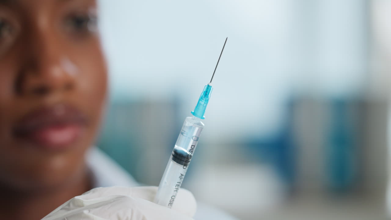 Close-up of a syringe with a needle held by a healthcare worker