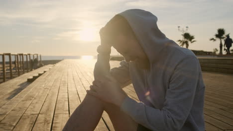 injured athlete sitting on pier at sunset