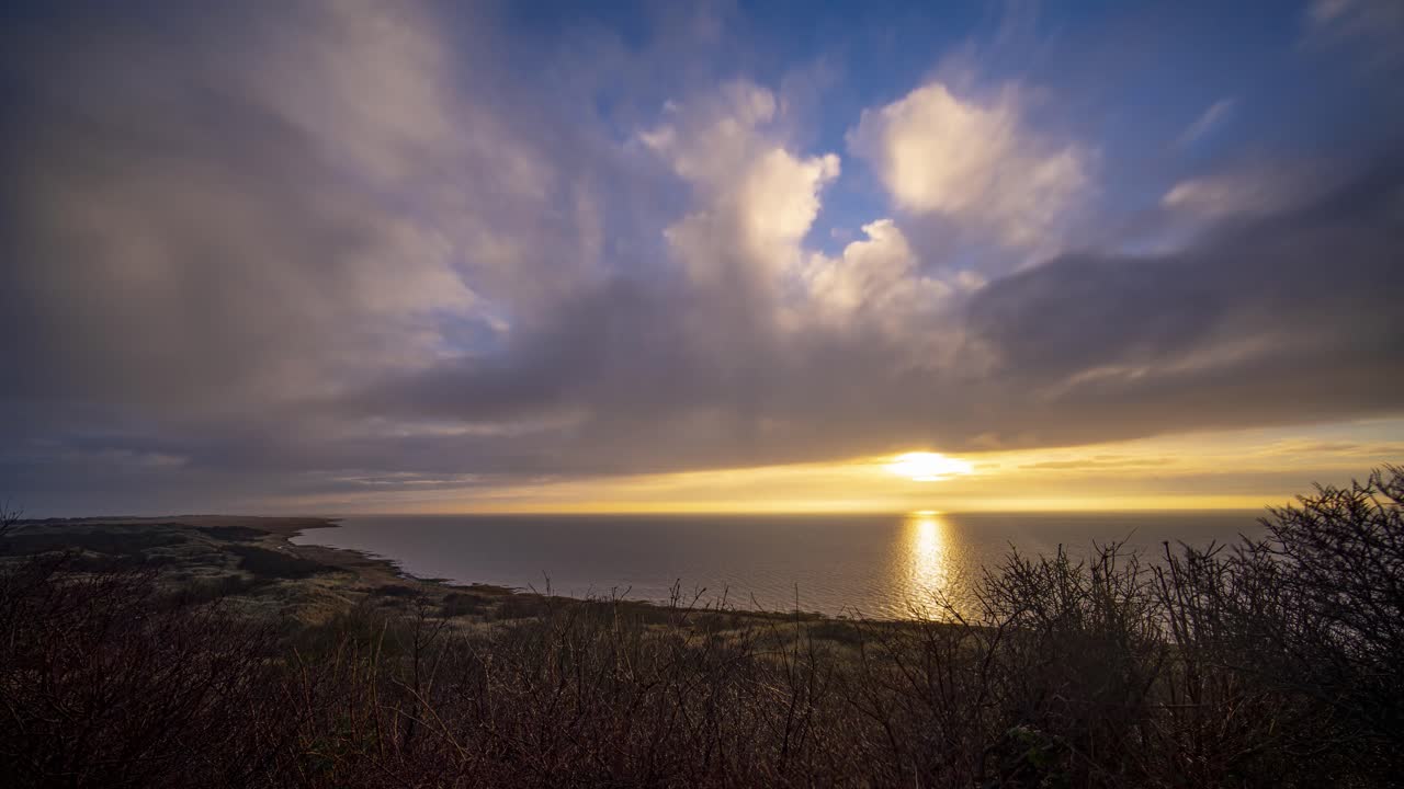lapso de tiempo de la mágica puesta de sol en la playa con nubes en movimiento durante la hora dorada