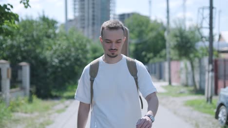 young man walking with guitar on street near forest