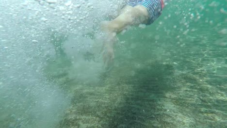 tiro bajo el agua a cámara lenta de niños nadando y creando destellos y burbujas en el mar