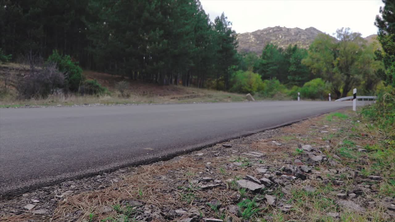Low-angle revealing shot of a mountain road in the middle of the forest. Camping trip concept.