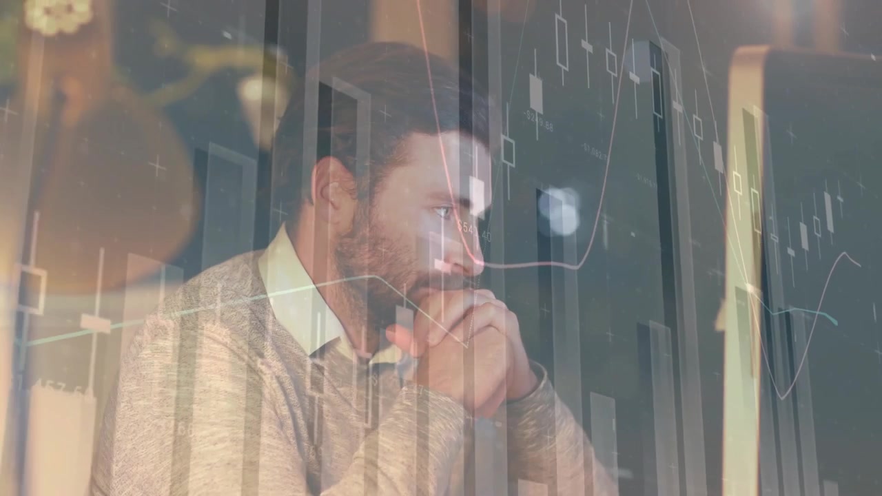 Analista finanziario che fissa il monitor del computer sulla scrivania, con grafici azionari fluttuanti.