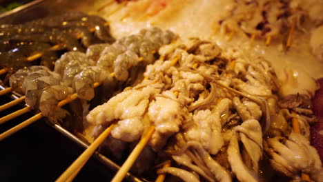 Thai-street-food,-squid-on-sticks-closeup-pan-left