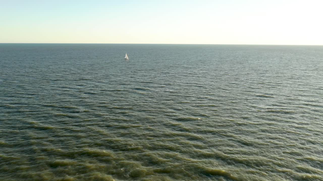vista aérea de un velero en la distancia navegando a través del océano