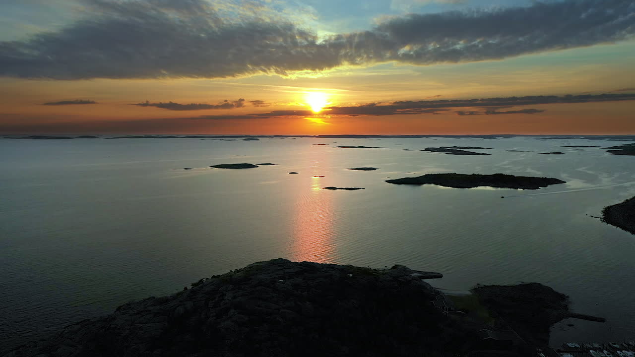 Aerial vivid sunset with intense and cinematic colours at a rocky coastline with a marina and islands in the archipelago