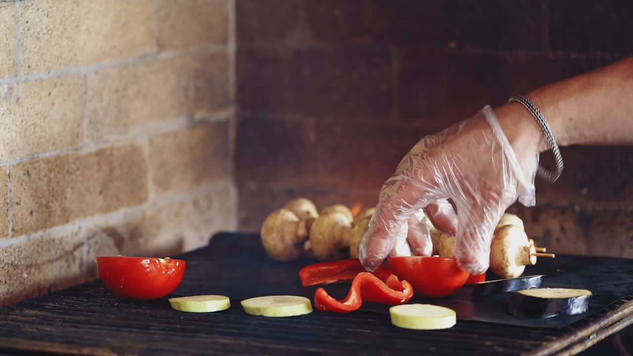 Grilling organic food. Hand of a professional cook putting fresh pieces of vegetables on a hot stove. Tasty composition on fire. Healthy food.