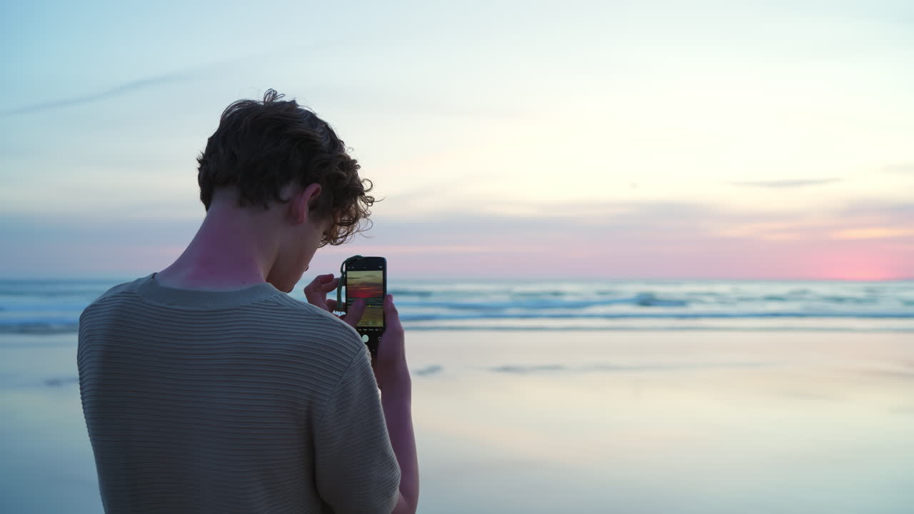 Young Man Taking Photos of Sunset on a Serene Beach