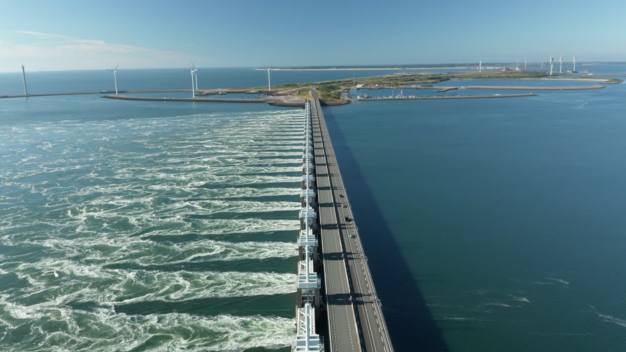 puente de carretera en la barrera de marejada ciclónica del este de scheldt con una vista lejana de los molinos de viento en zelanda, países bajos