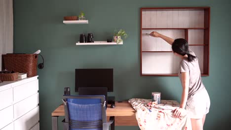 Asian-woman-painting-wooden-shelves-at-home