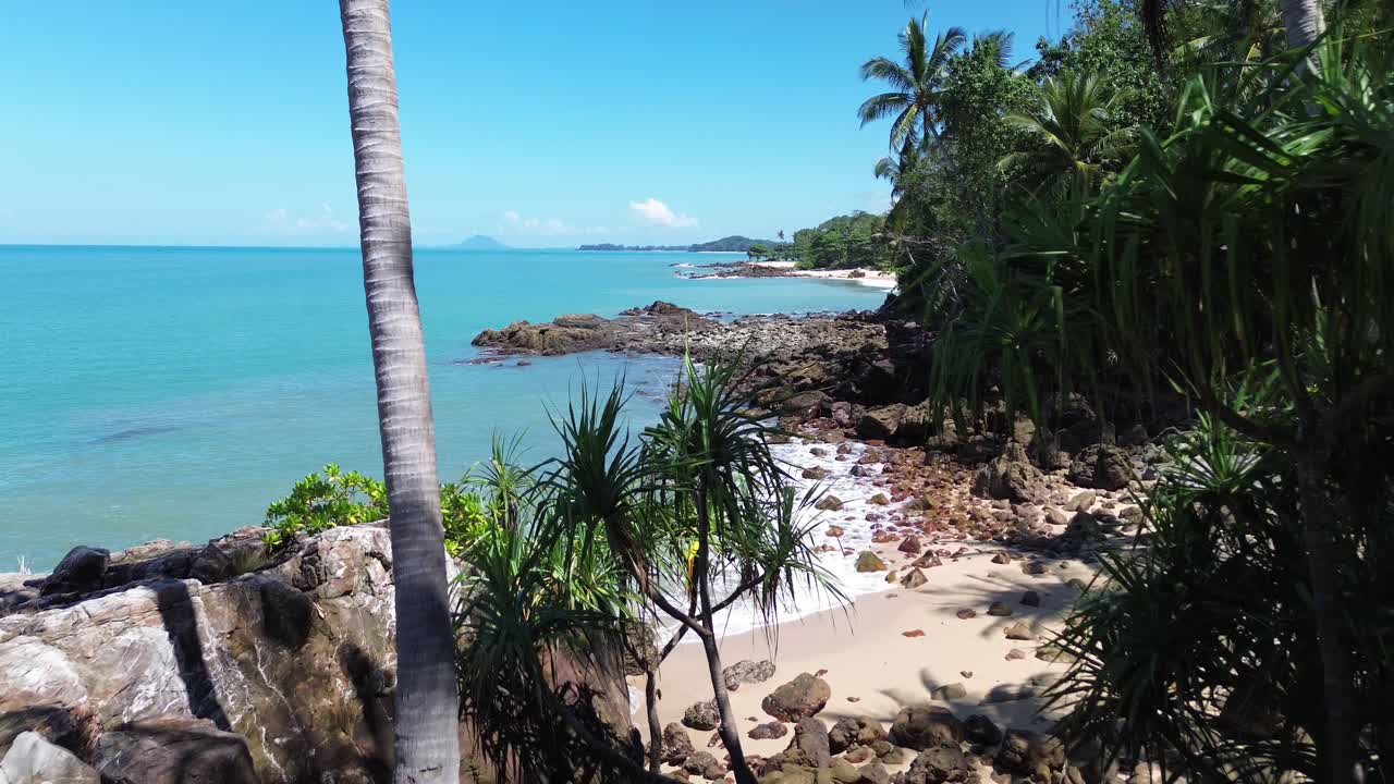 Vídeo aéreo con dron de una playa remota en Koh Lanta, Tailandia, con una costa rocosa, palmeras y agua turquesa cristalina, ideal para buceo, esnórquel y conceptos de viajes de naturaleza tropical.