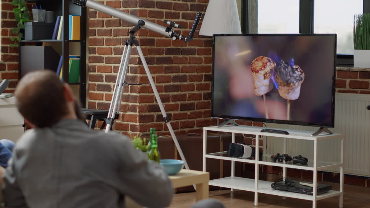 Happy people watching movie on television with beer and snacks