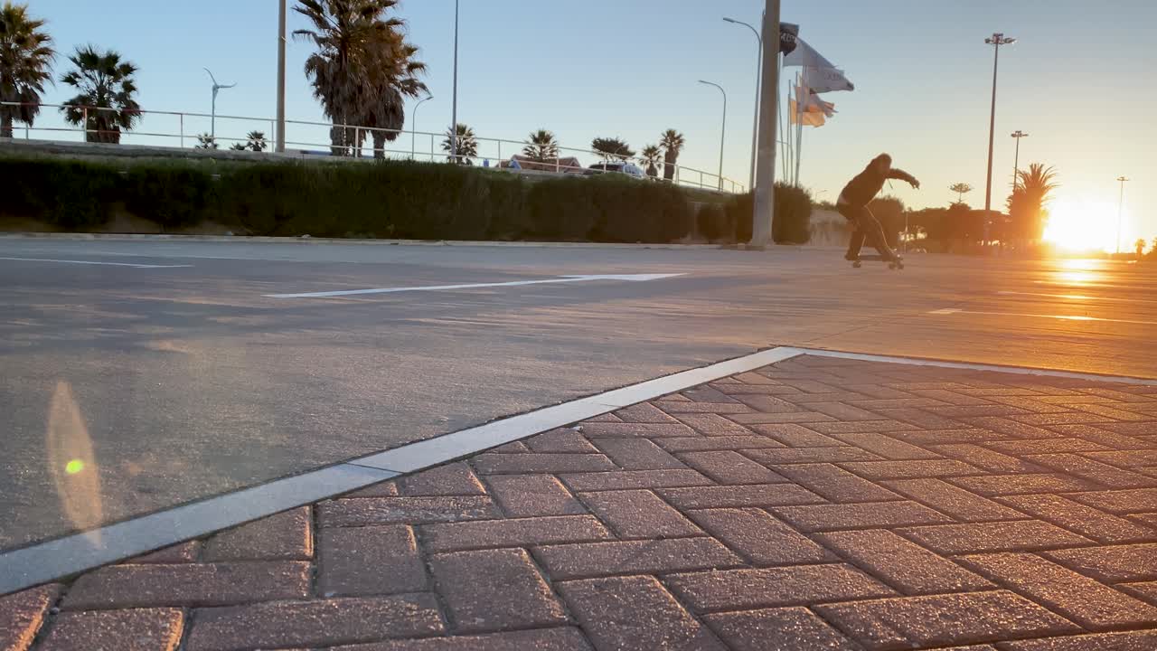 Stylish retro man riding a skateboard doing a surf style flip on a concrete park near the beach at sunrise in slow motion, young skateboarder ripping