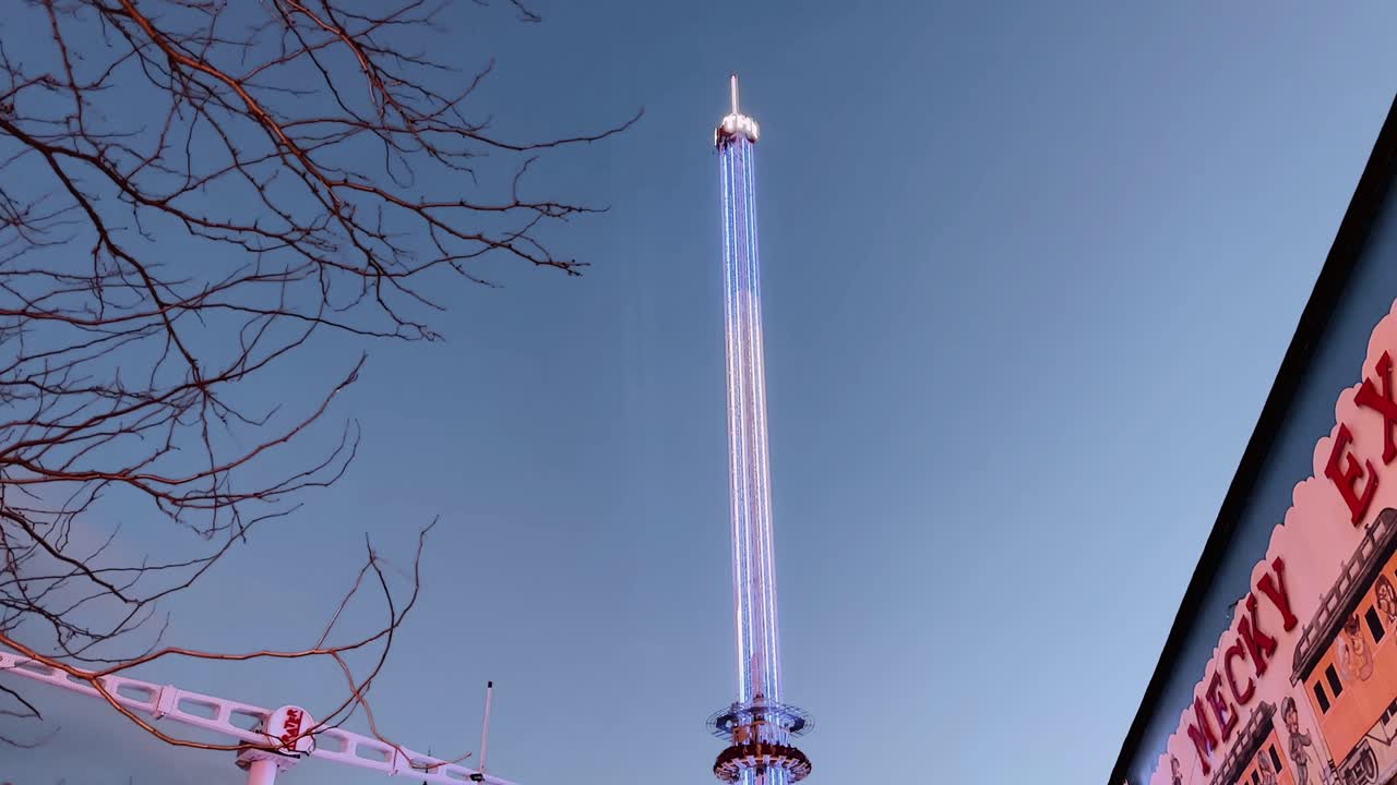 Tall illuminated amusement ride at Prater park Vienna Austria at dusk