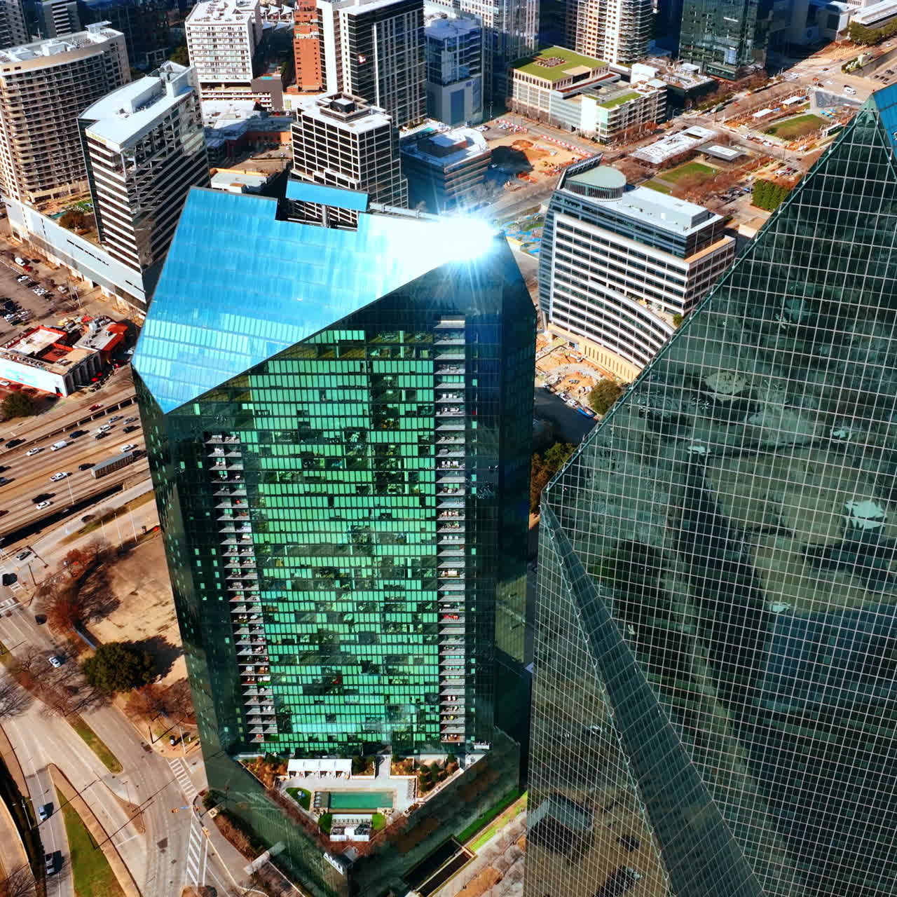 Vista aérea sobre os topos dos edifícios Fountain Place e AMLI Fountain Place. O sol a refletir do topo de uma torre. Centro de Dallas, Texas, EUA.