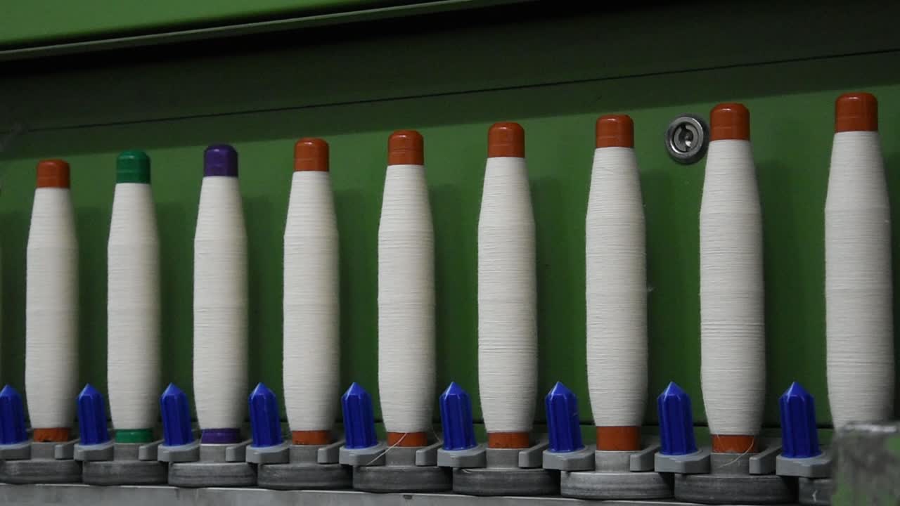 클로즈업 (close-up) 은 색 가닥을 가진 스핀링 머신을 작동시키는 것입니다.