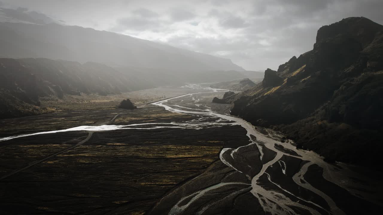 Dramatic aerial thor valley, glacial river flowing through black volcanic mountain, thorsm&ouml;rk cinematic moody Iceland
