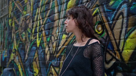 close up outdoor fashion portrait of young alternative style woman leaning against graffiti covered wall in london city street uk in real time 3