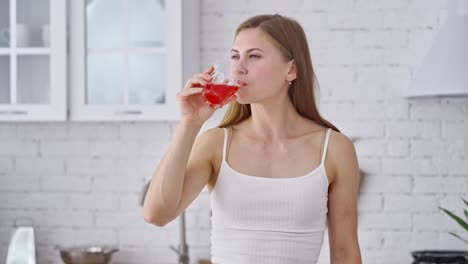 beautiful woman is drinking fresh at home. healthy girl holding glass with tasty juice and drinking happily in the morning. dieting concept.