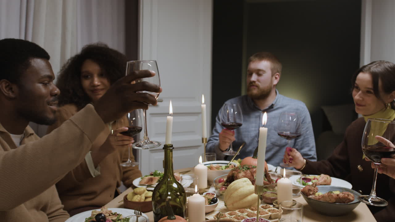 Friends enjoying a Thanksgiving dinner party, raising wine glasses for a toast