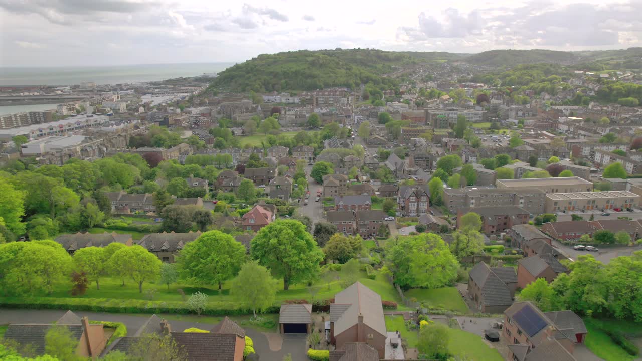 fotografía reveladora de una ciudad costera inglesa, dover, con colinas verdes en el fondo y un cielo nublado por encima