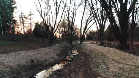 Toma-Aérea-De-Un-Estrecho-Canal-De-Agua-Con-árboles-Forestales-A-Ambos-Lados-A-Lo-Largo-Del-Campo-Rural-Por-La-Noche-En-Un-Pequeño-Parque-En-Wisconsin