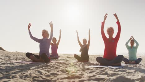 athletic women performing yoga in the beach