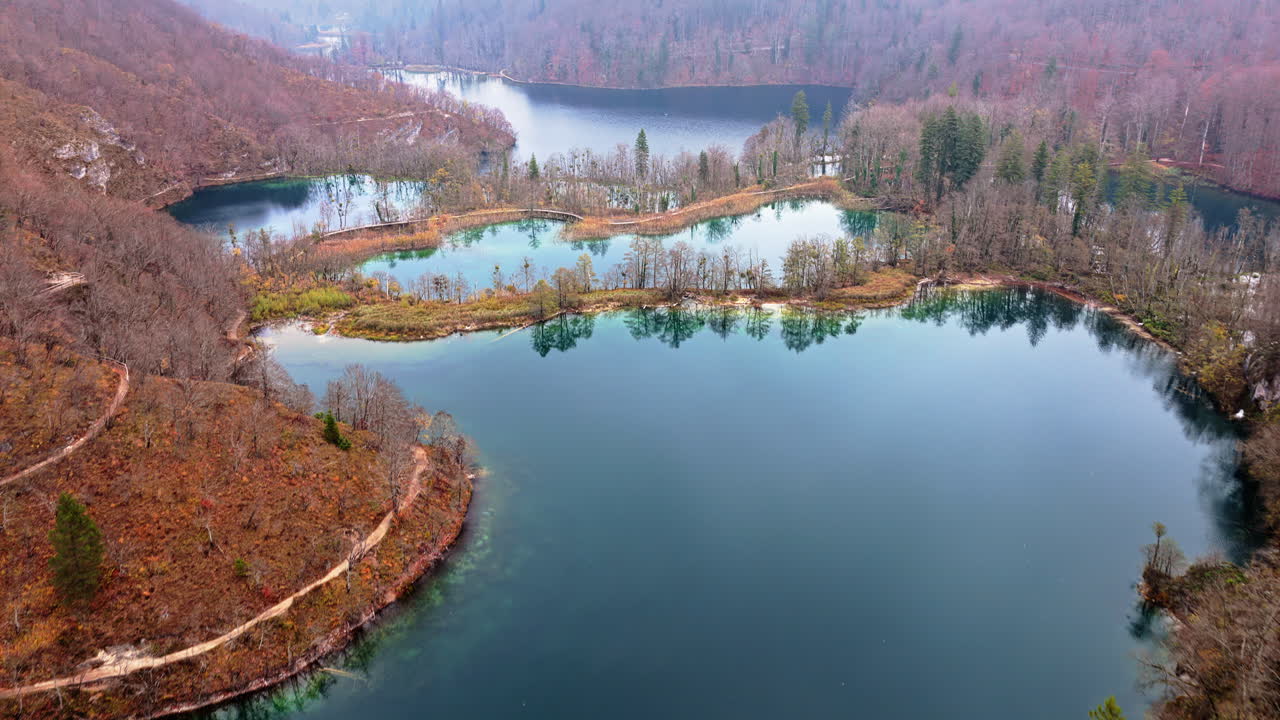 Aerial drone view of fog covered turquoise lakes separated by narrow forested islands at Plitvice Lakes, Croatia
