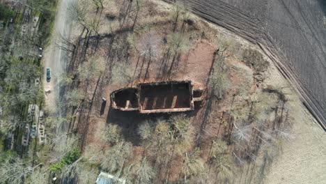 Aerial-descend-over-neglected-church,-wall-outline-remains-without-roof