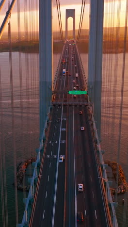 multi-lane road with cars going through the bridge. view from top on the bronx-whitestone bridge at the backdrop of east river. vertical video