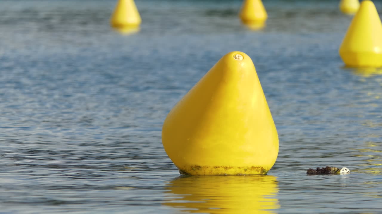 조용한 물 속에서 선박의 길을 나타내는 노란색 탐색 마커에 초점을 맞추고 배경이 흐려집니다.